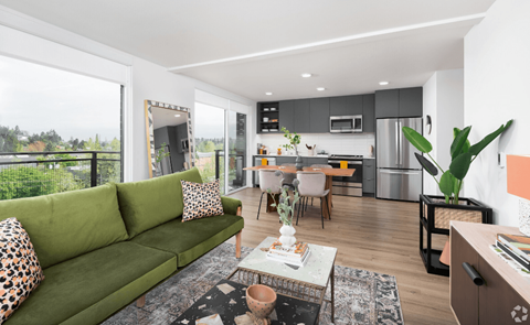 a living room with a green couch and a kitchen in the background